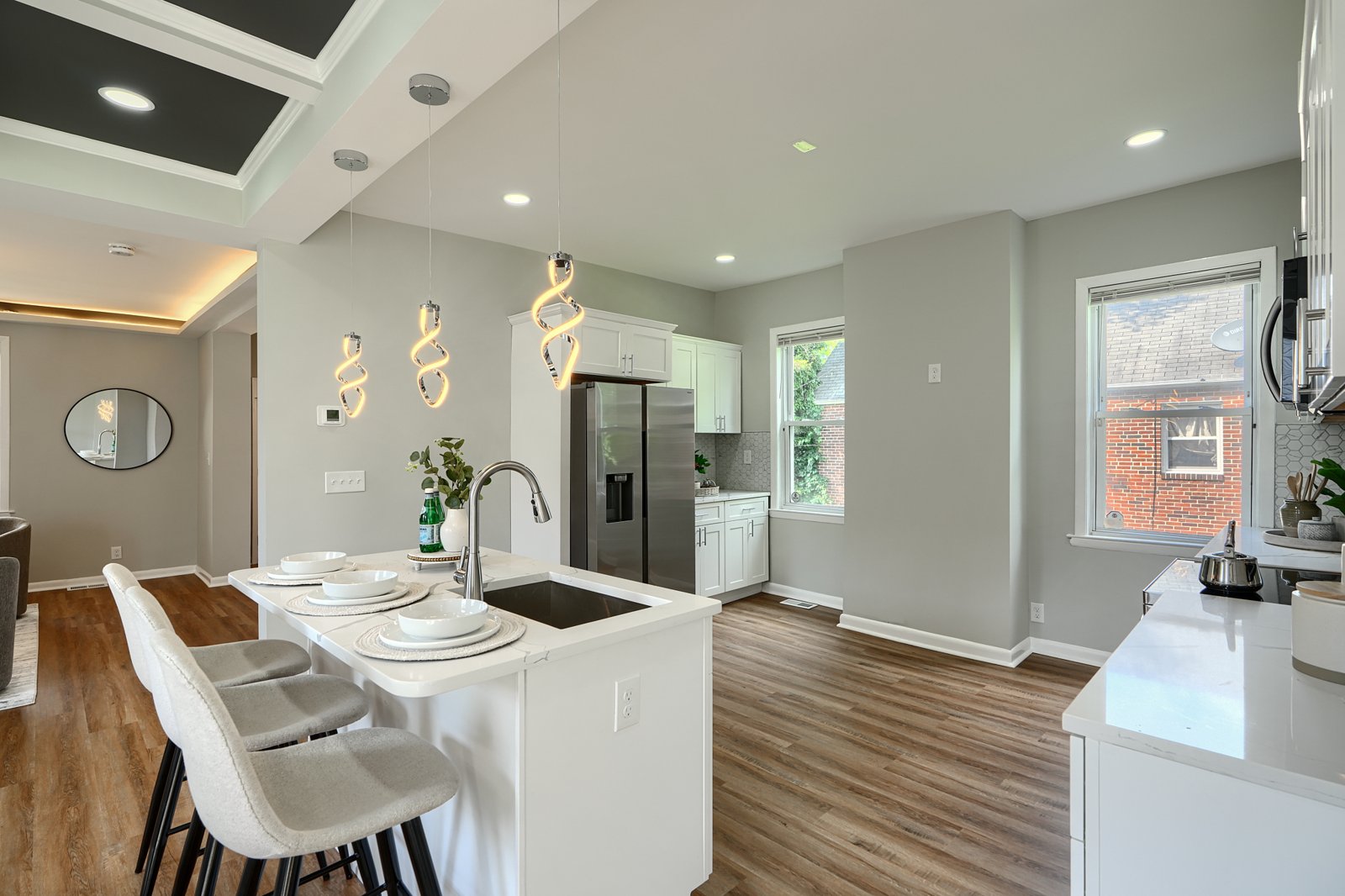 Kitchen bar seating with spiral pendants and stainless steel appliances
