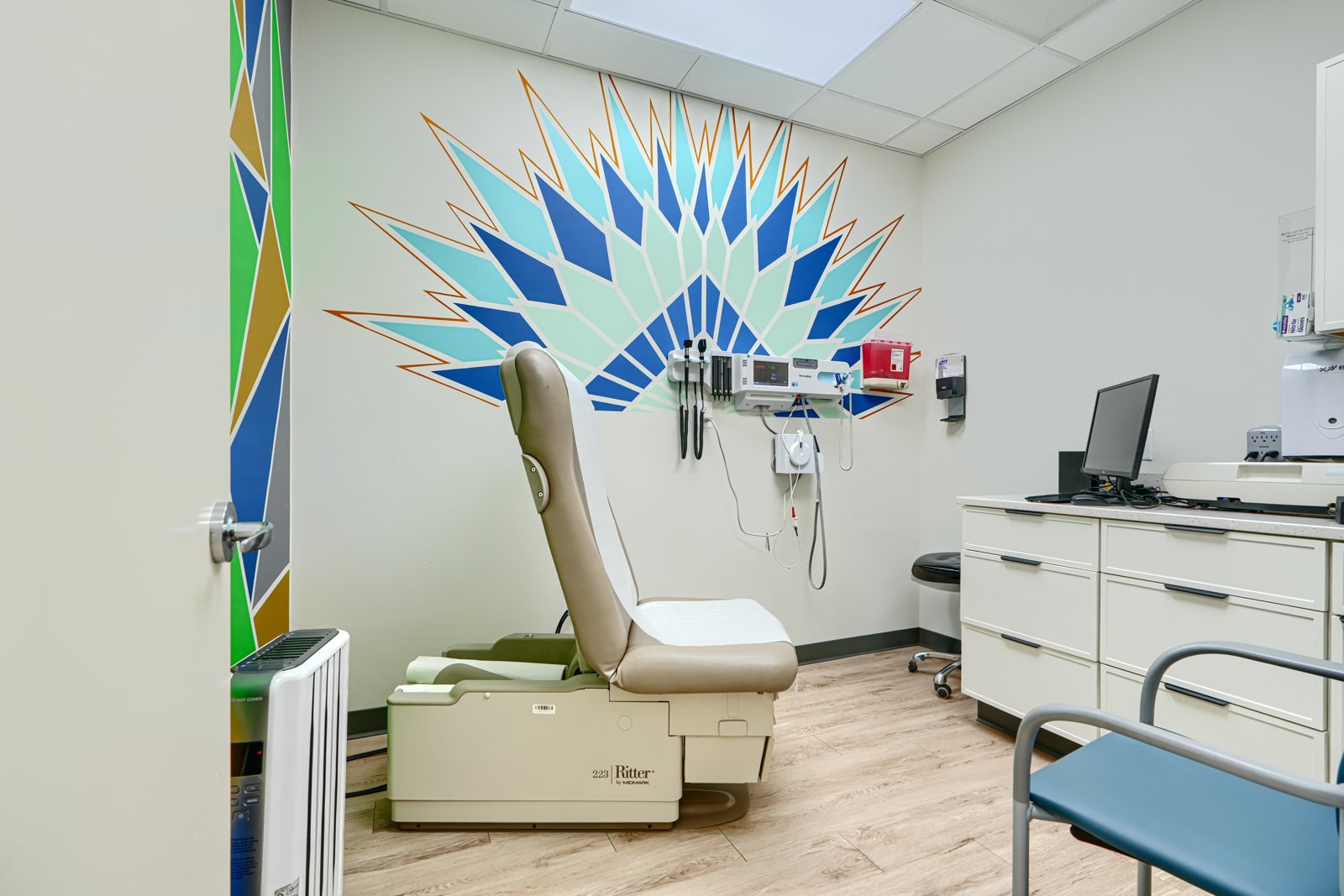 Exam room with teal and blue peacock fan wall mural
