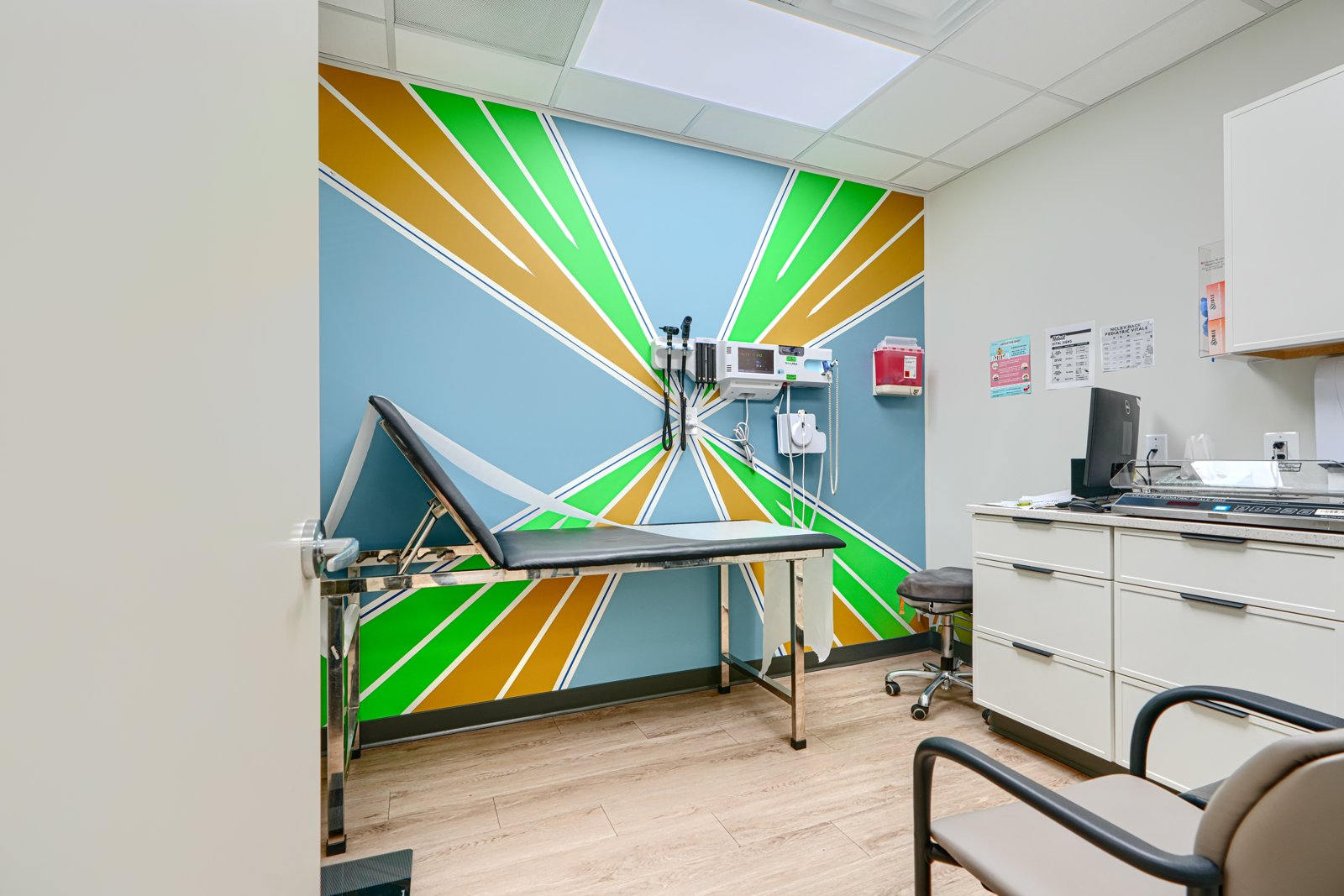 Exam room with green and gold radiating rays mural