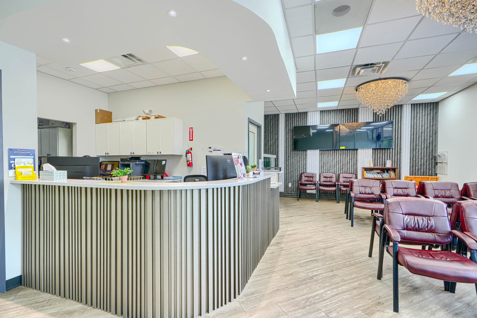 2827 Smith Ave - FastMed Urgent Care reception area with curved slatted desk and crystal chandelier