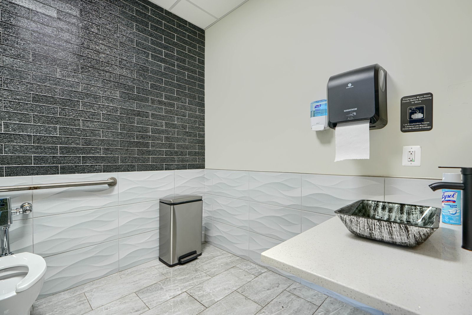Designer restroom with dark stone tile accent wall and vessel sink